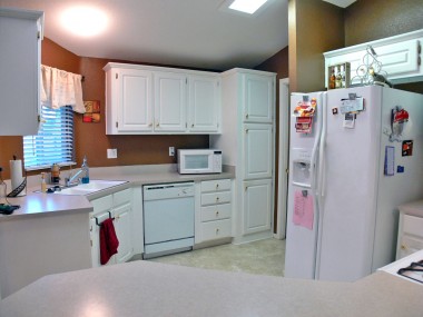 Alternate view of bright and cheery kitchen, with dishwasher, pantry, and doorway into separate laundry room.