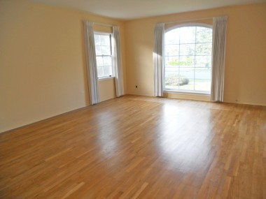 Spacious living room with original hardwood floors and large picture window.