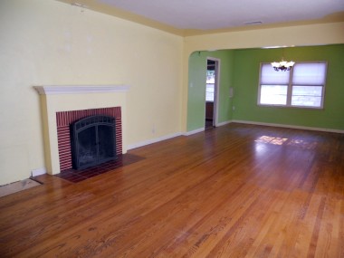 Living room with fireplace, original hardwood floors, and formal dining room with pocket door to kitchen.