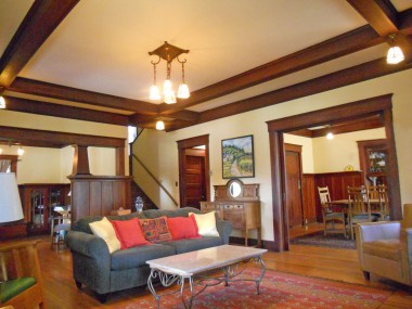 View of formal dining room to the right (through the open pocket doors), stairway to second floor and doorway at bottom of stairs leading to kitchen, and to the far left is the parlor. This is another perfect vantage point to admire the box beam ceiling.