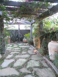 Elegant backyard sitting area under the bougainvillea covered pergola, complete with pottery landscaping and accent lighting.