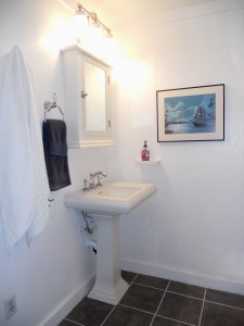 Hallway bathroom with tile floor and pedestal sink. Sellers in process of installing brand new spa tub.