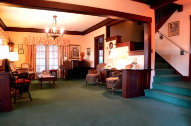 Note the original 1912 wood throughout, as well as framing the spacious living room which is large enough to display a grand piano, as you can see in the far corner.