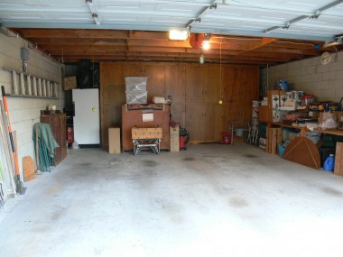 Garage was made out of block in the 1990s and boasts lots of homemade cabinetry and an automatic garage door opener on a roll-up garage door.