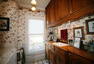 Convenient upstairs laundry room with tile floor, real tin (period accurate) ceiling, with sink and antique cupboards.