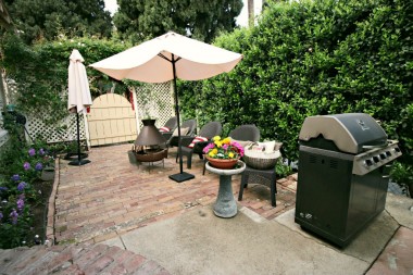 Side patio off the kitchen with privacy hedges and room for bbq and lots of blooming flowers!