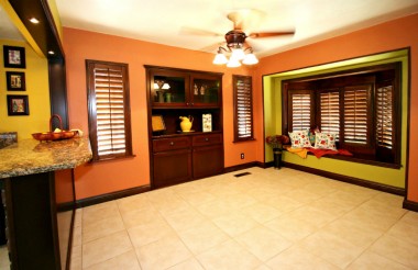 Formal dining room with tile floor, original built-in hutch, window shutters, breakfast bar, and window seat.