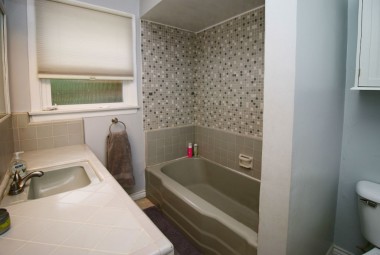 Hallway bathroom with shower in tub.