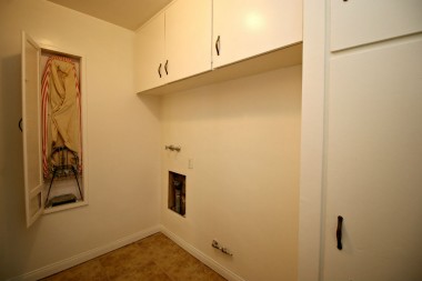 Separate laundry room with lots of cabinetry, tile flooring, and original built-in ironing board.