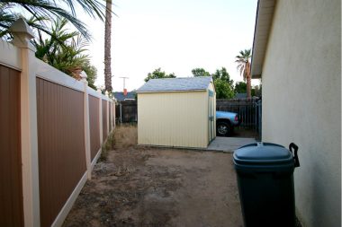 Gated RV/boat parking area on side of house with shed.