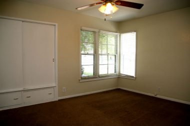 Largest bedroom facing front of the house, with extra large closet, corner windows, carpeting, fresh paint, and ceiling fan.