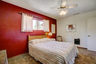 Front bedroom on other side of the house, with carpeting and ceiling fan.