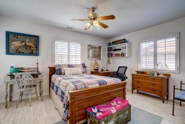 Master bedroom suite with window shutters, ceiling fan, and newer flooring.