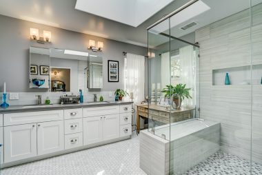 Remodeled private master bathroom with skylight, glass shower, tile floor, and dual wash basins.