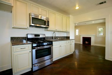 Remodeled eat-in kitchen with granite counter tops, stainless steel gas stove and built-in microwave and sink, with view into family room, complete with cozy fireplace.