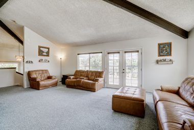 Super spacious living room with beamed ceiling overlooking the front yard, with French doors leading to a balcony with lovely views of Riverside.