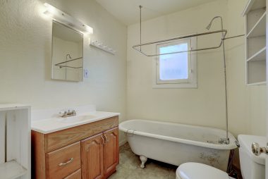 Bathroom with what could be original claw foot tub. There's some discoloration on linoleum flooring around tub from children splashing while bathing, but a plumber was consulted and it's merely cosmetic, as there is no water damage. 