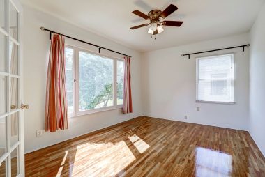  Front bedroom with French doors (simply add curtains for privacy), ceiling fan, and recently refinished original hardwood floors.