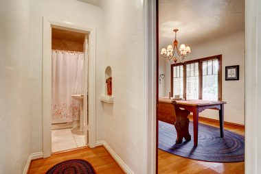 View of old fashioned telephone alcove leading into the hallway bathroom with pedestal sink and bathtub.