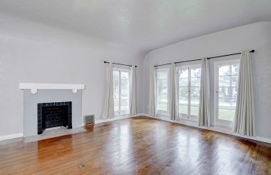 Outstanding living room with semi-barrel ceiling and floor to ceiling original window frames, and original hardwood floors.