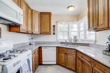 Updated kitchen with granite counter tops, new flooring, dishwasher, gas stove, built-in microwave, and corner sink with double pane windows.