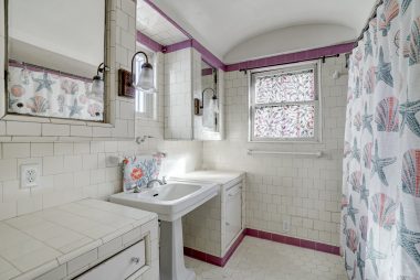 Vintage hallway bathroom with pedestal sink and shower in tub.