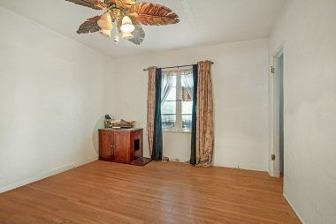 Third of three bedrooms with original hardwood floors, ceiling fan, and walk-in closet.