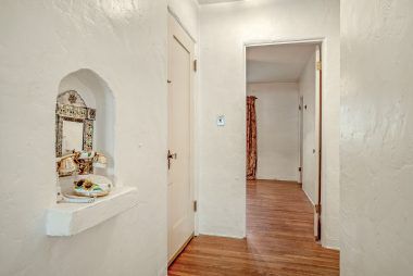 Hallway to bedrooms with telephone alcove and original hardwood floors.