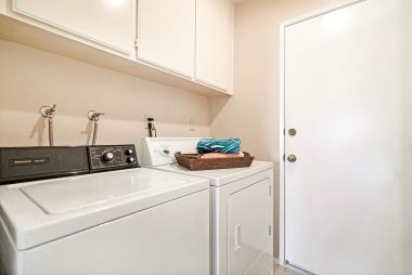 Indoor laundry room with doorway leading to attached garage.