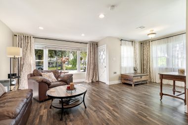 Luxury waterproof vinyl plank flooring throughout the home, with large picture window and recessed lighting in spacious living room.