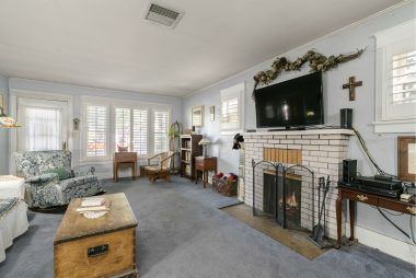 Living room with fireplace and carpeting over hardwood floors.