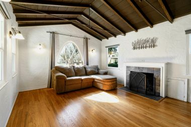 Lovely living room with hardwood floors, and high-peaked ceiling with original exposed hand-painted wood beams.