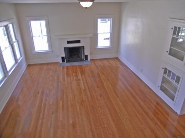 View of large living room with newly refinished original hardwood floors.