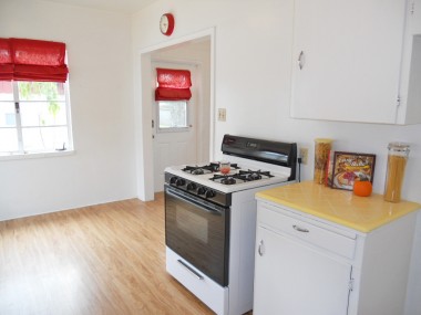 Alternate view of kitchen with original yellow tile counter top. Access door leads to the expansive backyard.