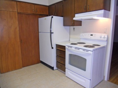 Alternate view of kitchen with refrigerator and newer stove (that both stay), along with a stackable washer/dryer unit that also stays.