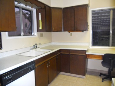 Dishwasher, newer tile floor, lots of cabinetry, and a desk in the bright kitchen.