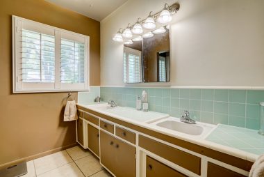 Bath with double sinks, retro counter tile, and newer tile floor.