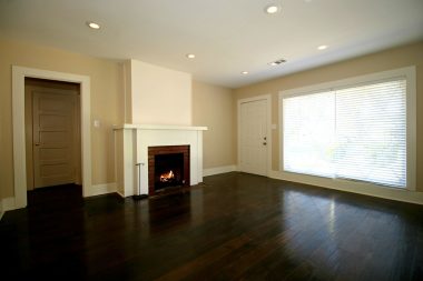 Living room with front entrance, newer wood floors, recessed lighting, large windows allowing in lots of natural light, and gas fireplace.