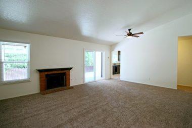 Spacious living room with wood-burning and gas fireplace, cathedral ceiling, new double pane windows, new ceiling fan, new carpeting, new paint.