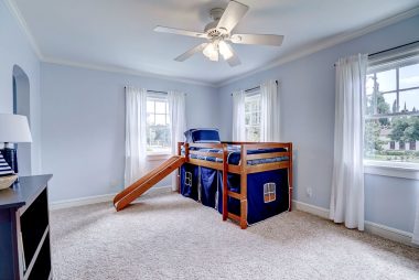 The fourth of four upstairs bedrooms with carpeting, ceiling fan, and a smaller walk-in closet.