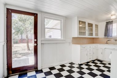 Cute kitchen with tile counter tops and glass-fronted cabinets.