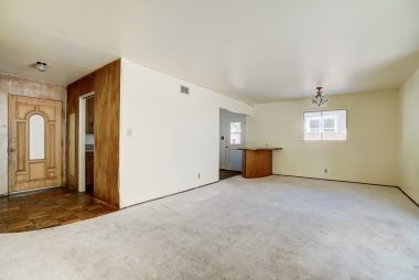 Living room with view of front door entry and kitchen area.