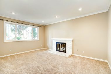 Step-down formal living room with gas and wood-burning fireplace and recessed lighting.