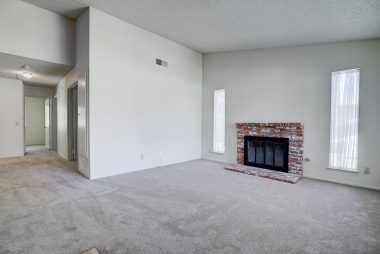 Living room fireplace, cathedral ceiling (a single story that feels very spacious) with view into hallway leading towards bedrooms.