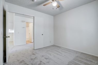 Front bedroom with double door entry, brand new carpet, and ceiling fan.