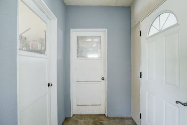 Enclosed step-down breezeway with large storage room to the left, garage straight ahead, and exit door to side yard facing Brentwood Avenue.