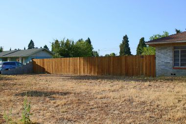 View of fenced vacant lot next door which is also for sale.