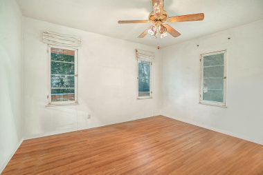 Second of three bedrooms with original hardwood floors, ceiling fan, and walk-in closet.