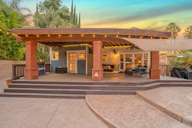 Twilight view of the back covered patio which is ideal for year-round entertaining. Note the custom-stamped concrete surrounding the pool area.