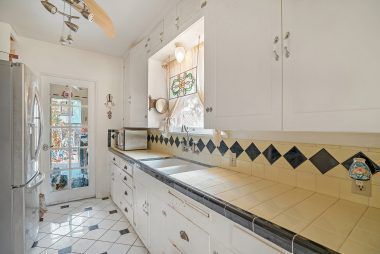 Vintage kitchen with tile floor and French door leading to indoor laundry room.